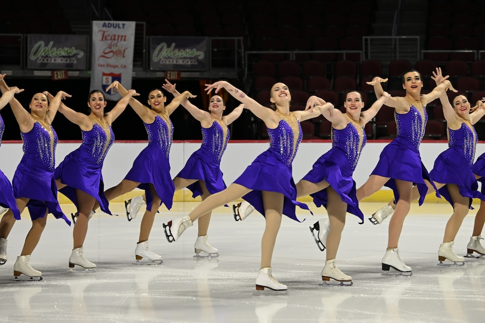 Brooke with her team as they do an artistic flair with their arms while skating in two lines.